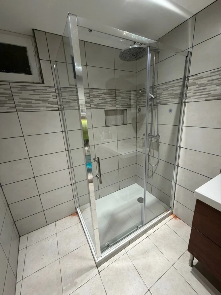 Rénovation de douche italienne moderne avec paroi vitrée et carrelage gris à Bordeaux réalisée par KMS