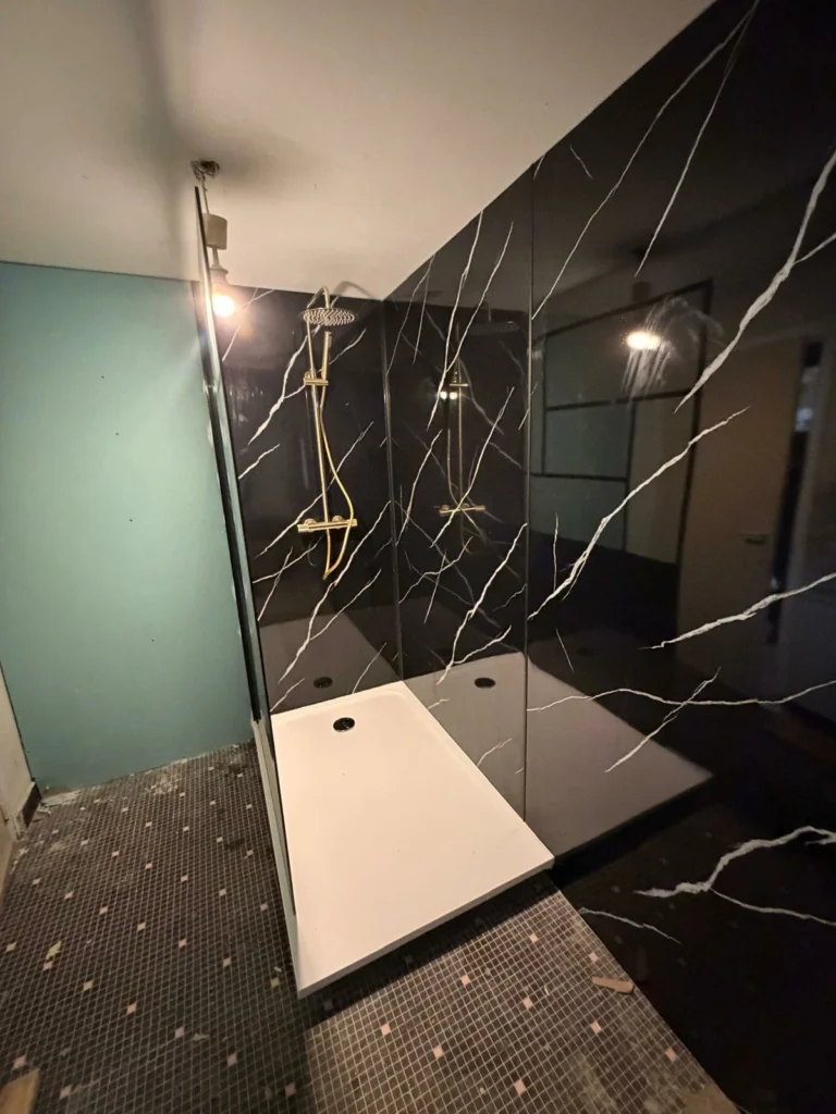 Rénovation de douche italienne avec parois effet marbre noir et robinetterie dorée à Bordeaux réalisée par KMS